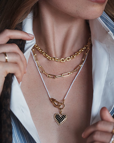 Women wearing  gold and pearl jewelry with a charm