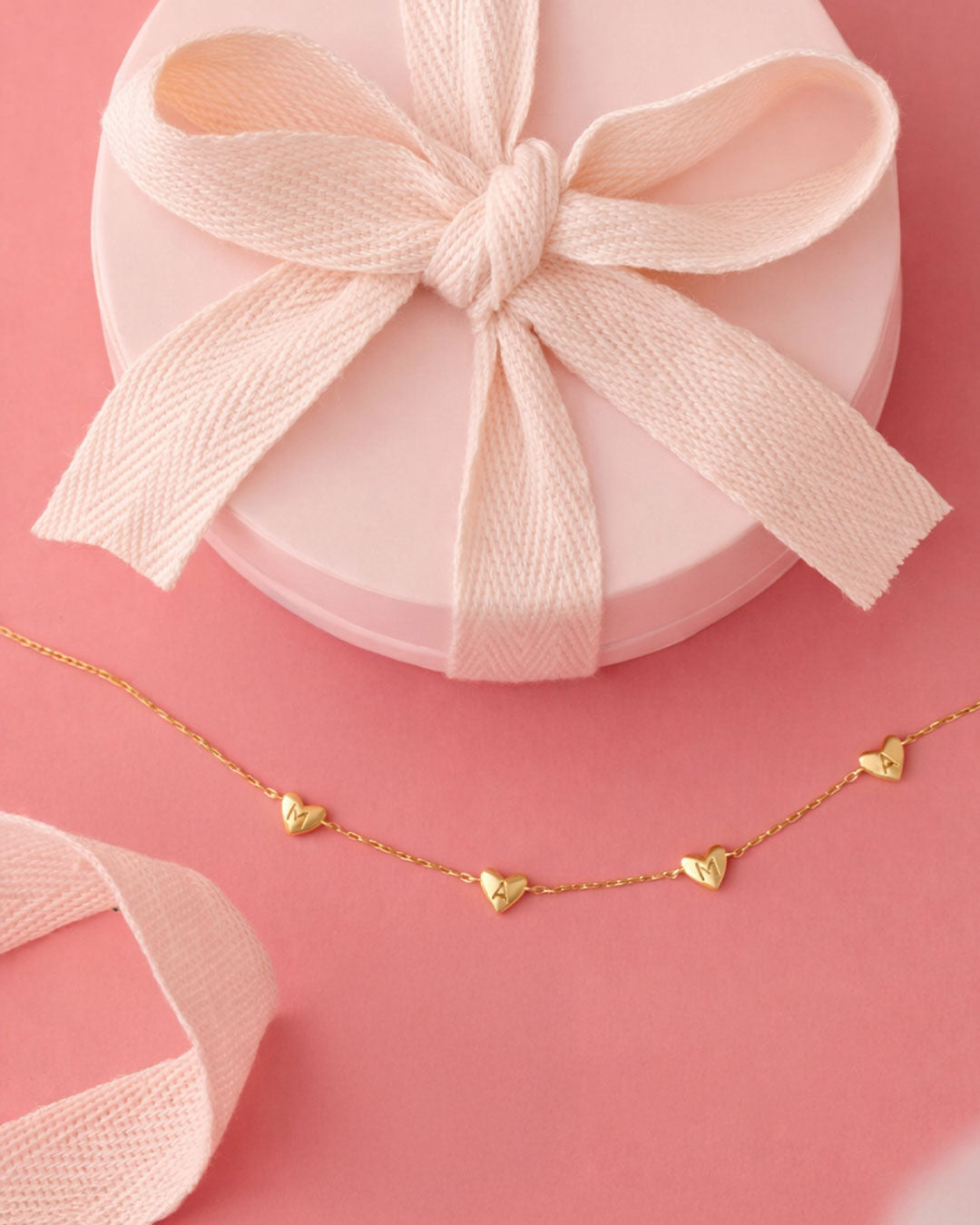 Gold necklace with heart pendants on a pink background