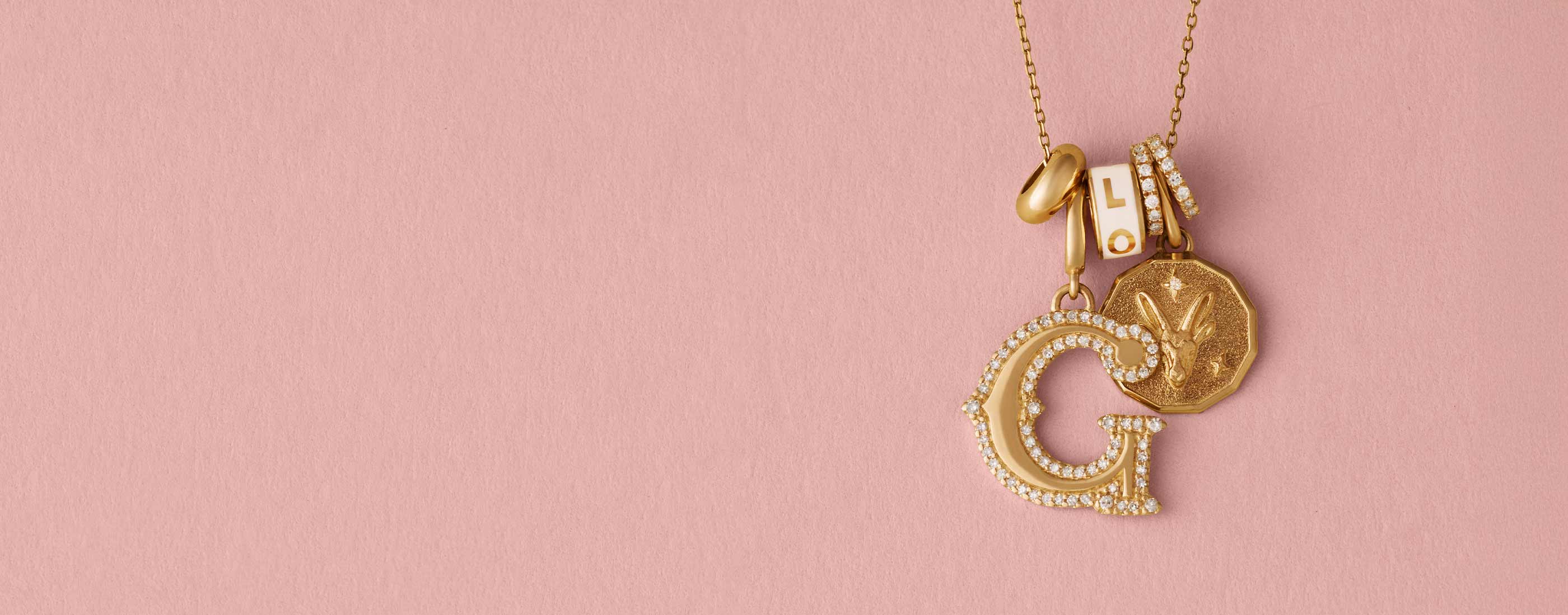 Gold necklace with charms on a pink background