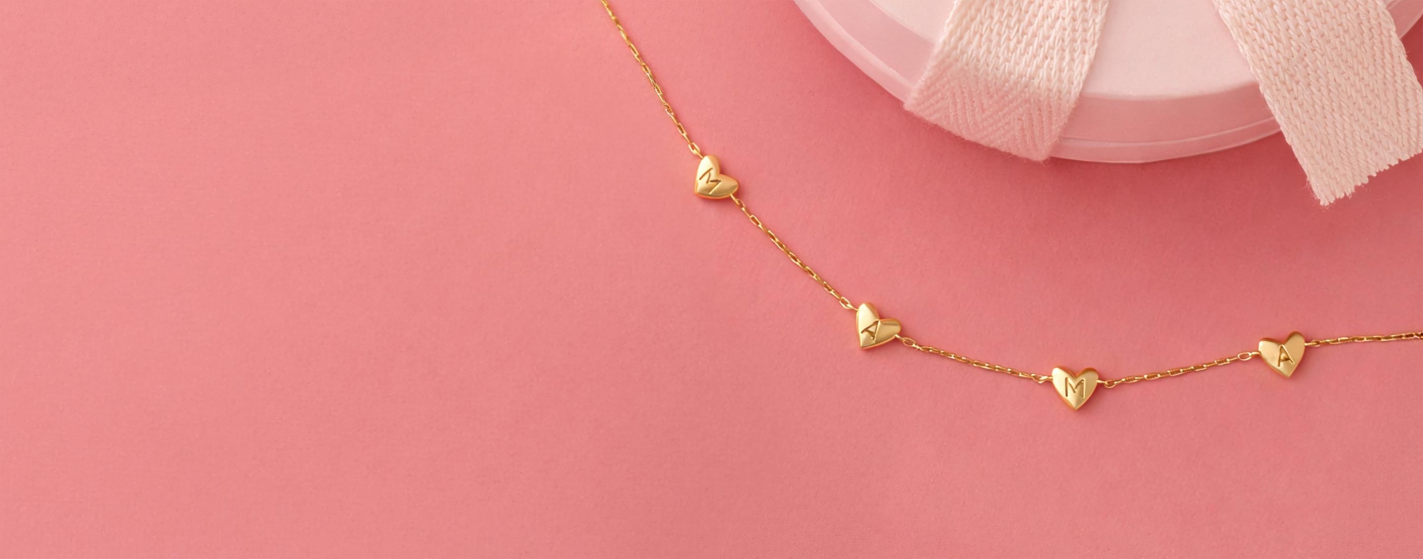 gold plated heart mama bracelet on a pink backgorund