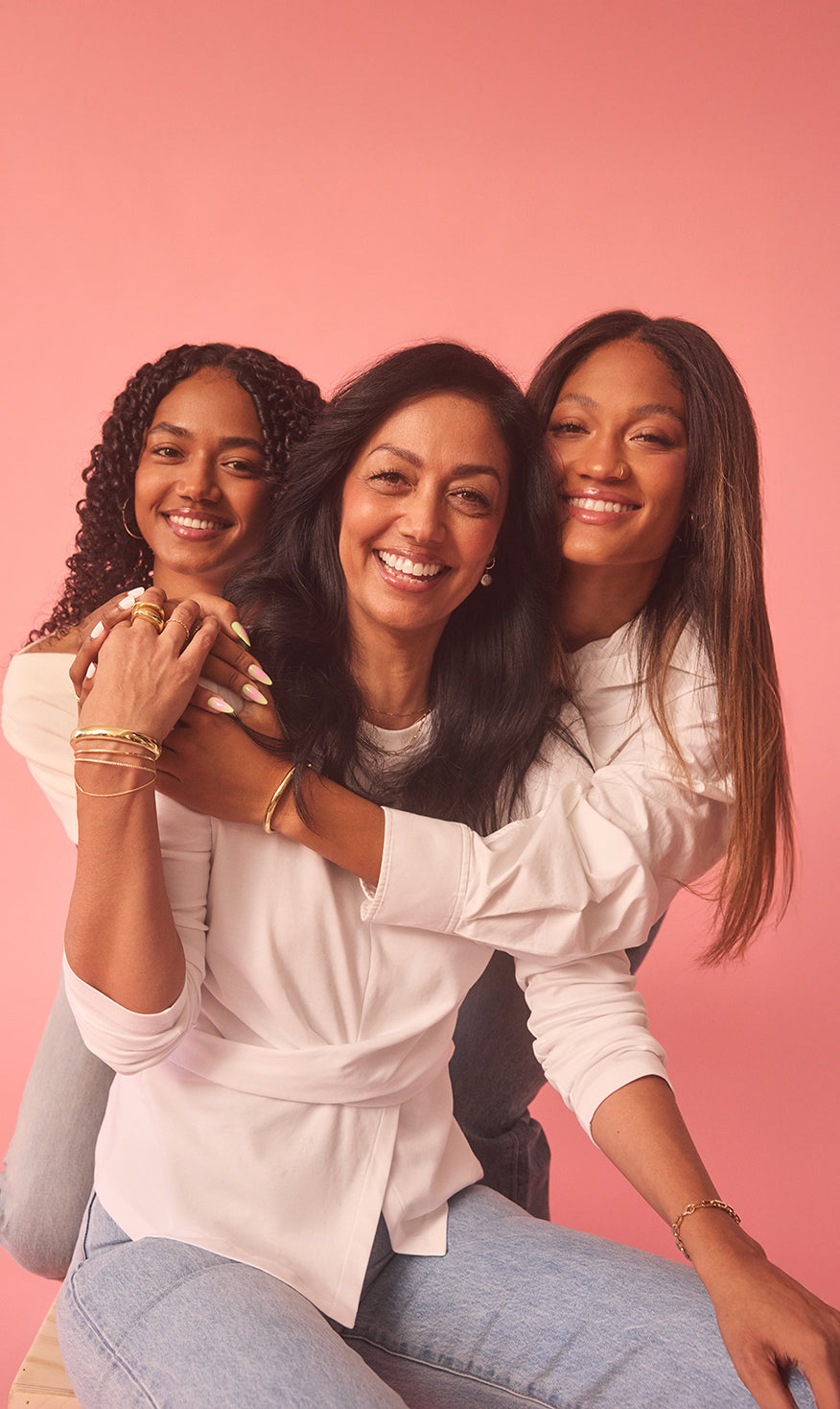 Felicia and her daughters posing together against a pink background