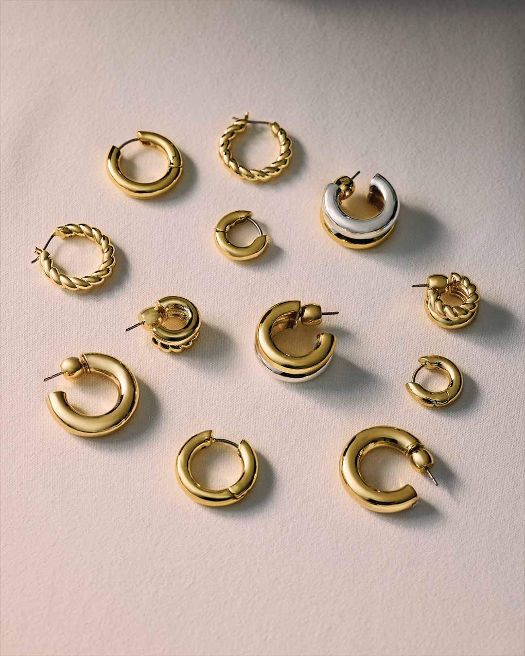 Collection of gold hoop earrings on a light background