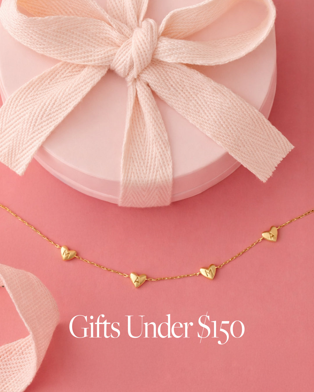 Gold necklace with heart pendants on a pink background with a gift box. 'Gifts Under $150' text