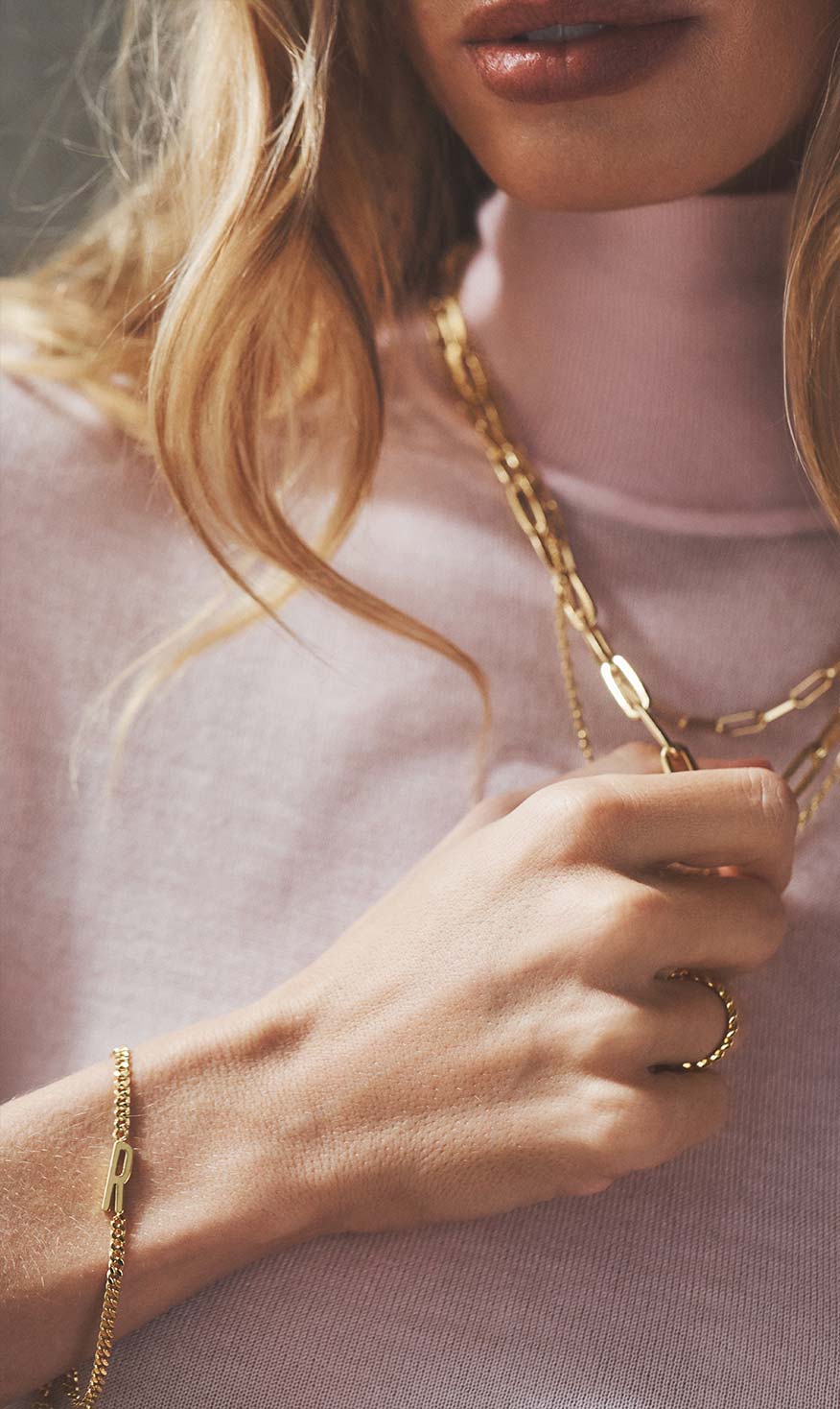 woman in light pink shirt with gold stacking