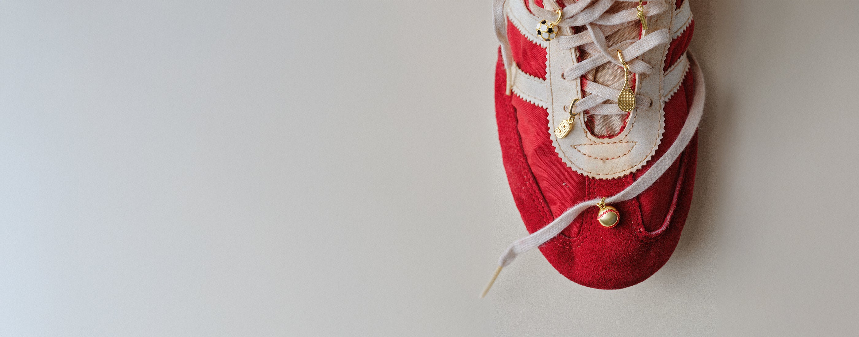 Red sneaker with gold plated sports and number charms on it
