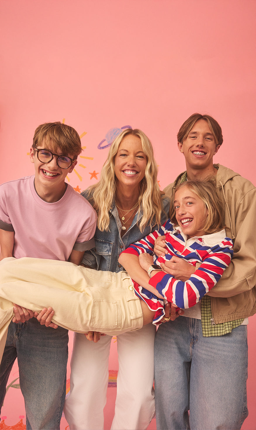 Lara and her 3 sons posing together against a pink background