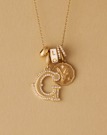 Gold necklace with letter 'G' pendant on a yellow background